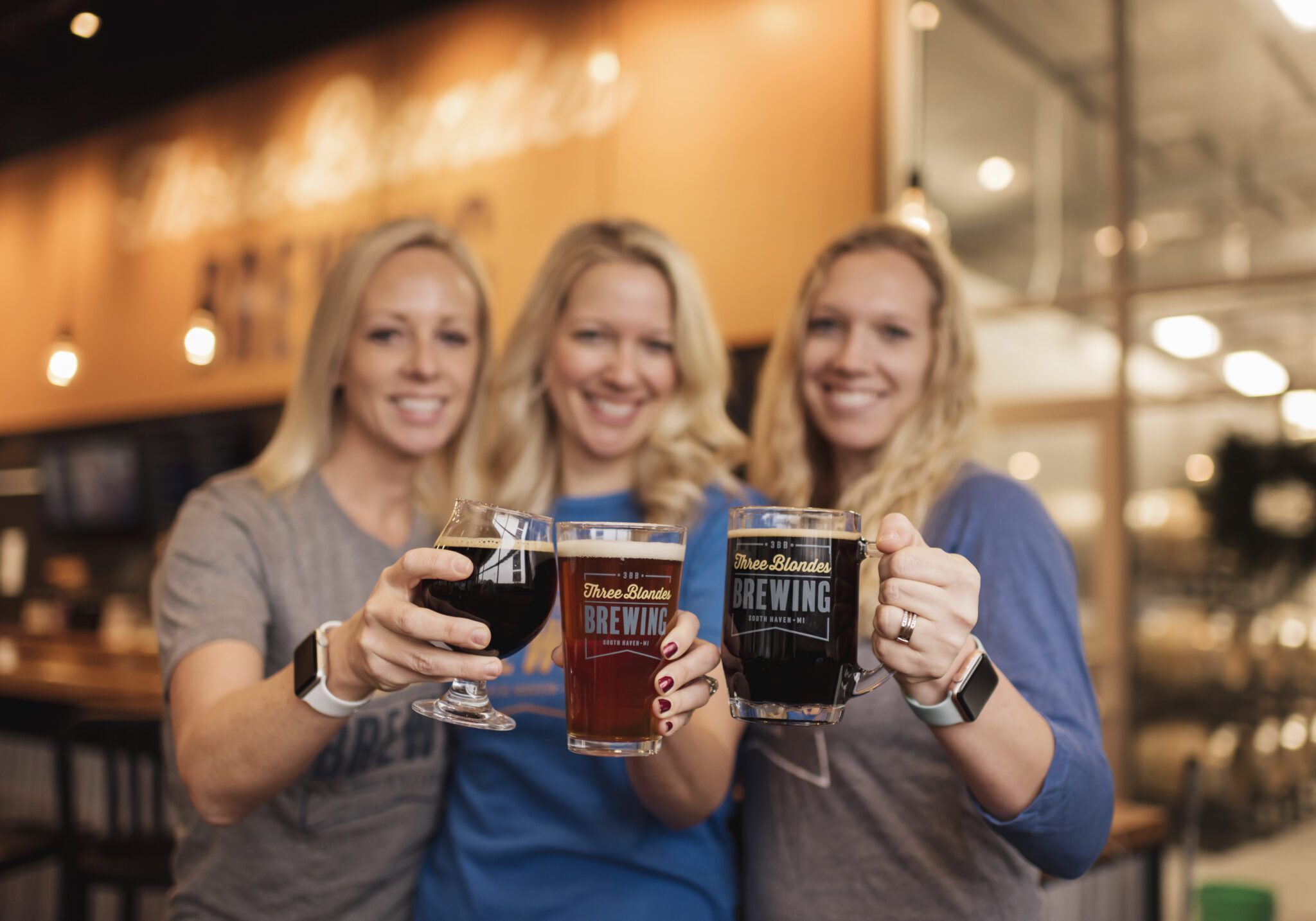 3 blondes cheersing in front of bar